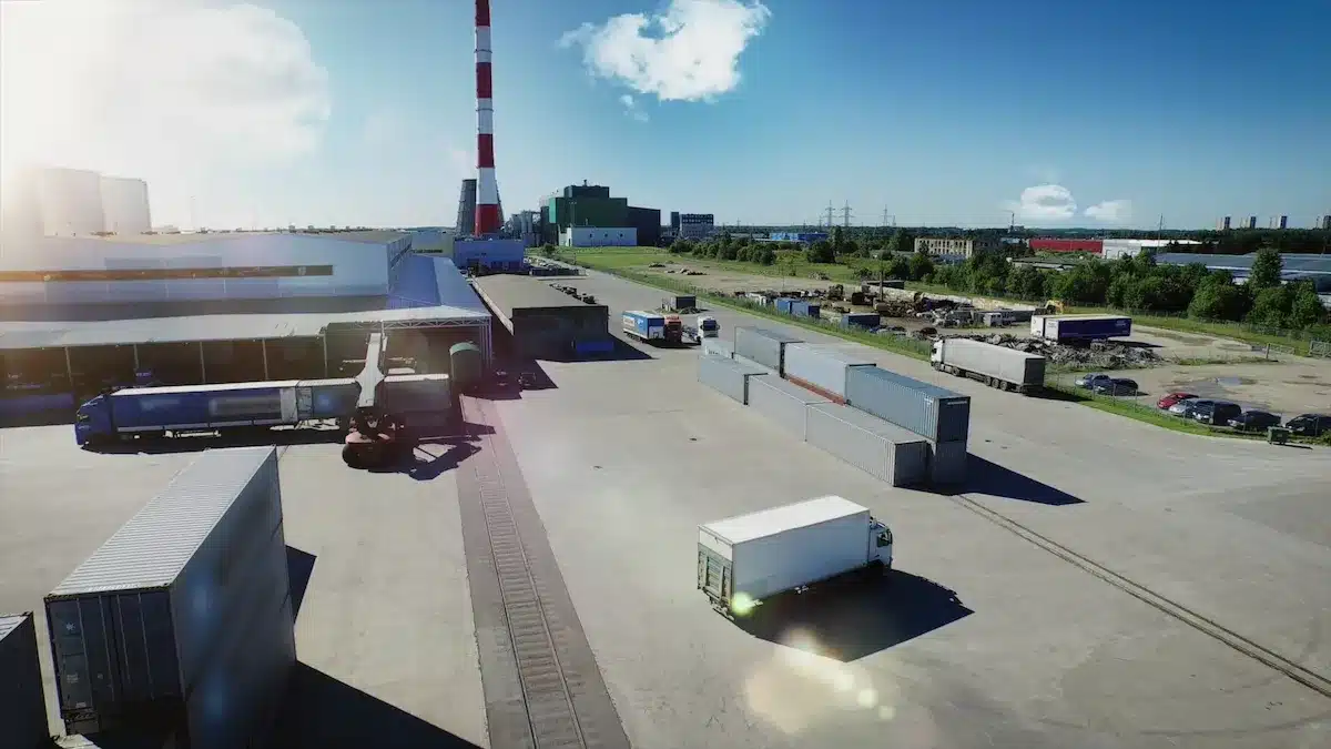 Overhead view of a large warehouse, trucks, and a parking lot